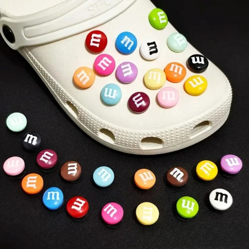 White clog shoe with colorful M&M-themed buttons on a black background