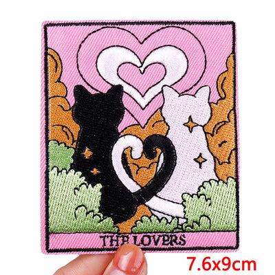 Patch with cats and hearts design held by a hand, on a pink background