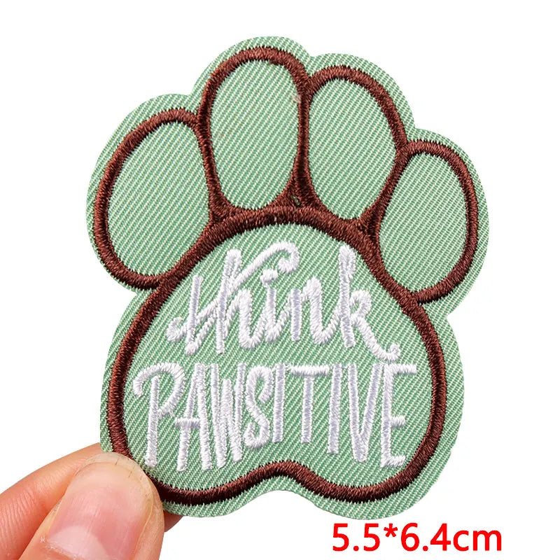Paw-shaped patch with 'Think Positive' text held by a hand on a white background