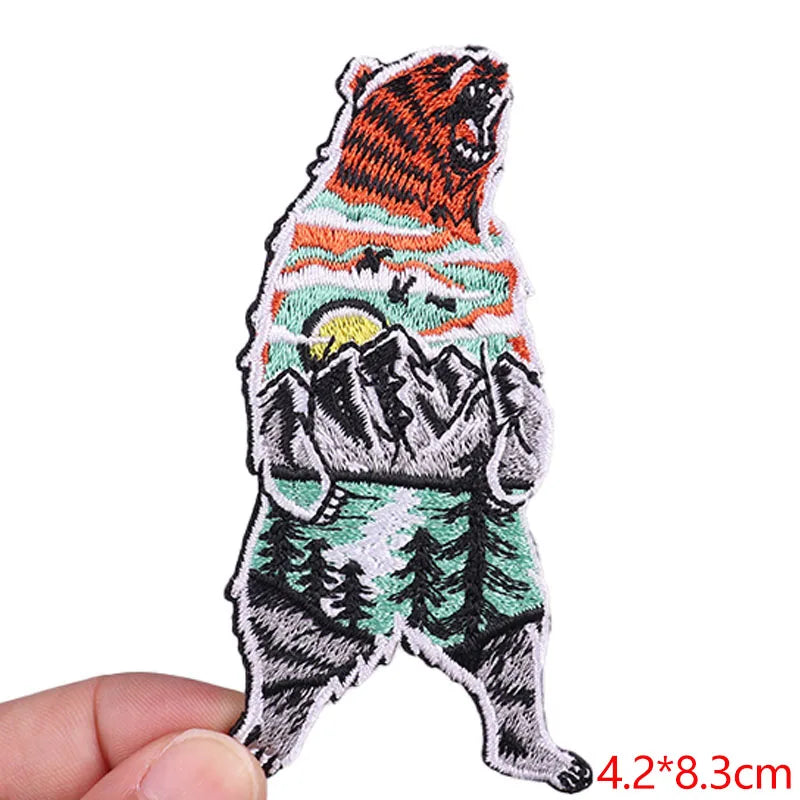 Embroidered patch of a bear with mountain design held by a hand on a white background