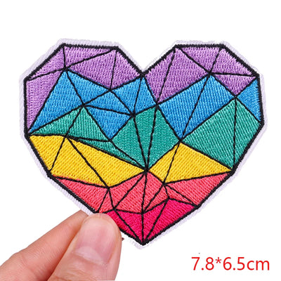 Colorful geometric heart patch held by a hand with dimensions displayed.