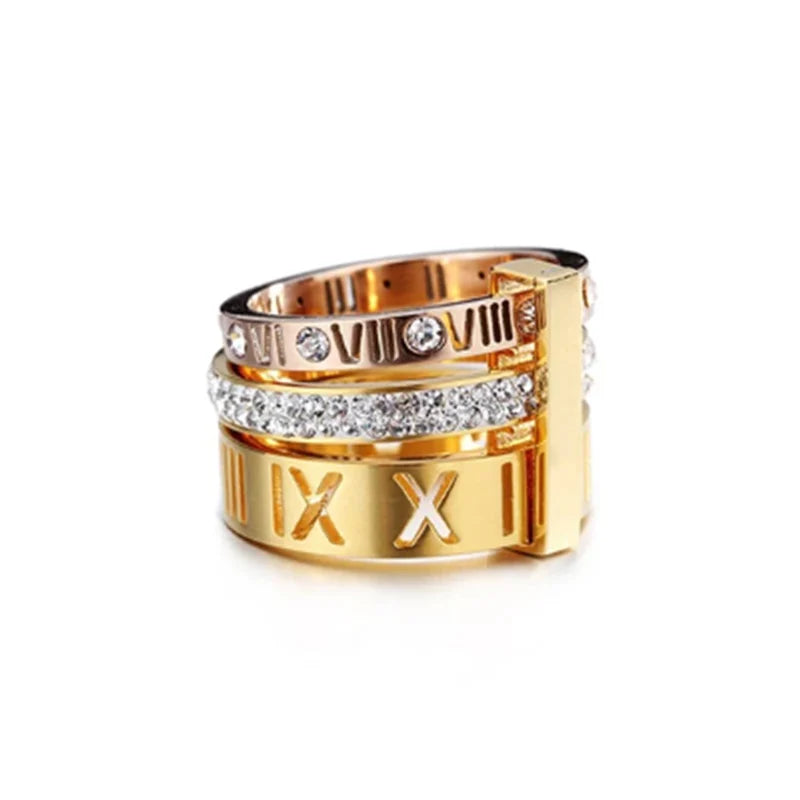 Gold ring with Roman numeral design and embedded crystals on a white background