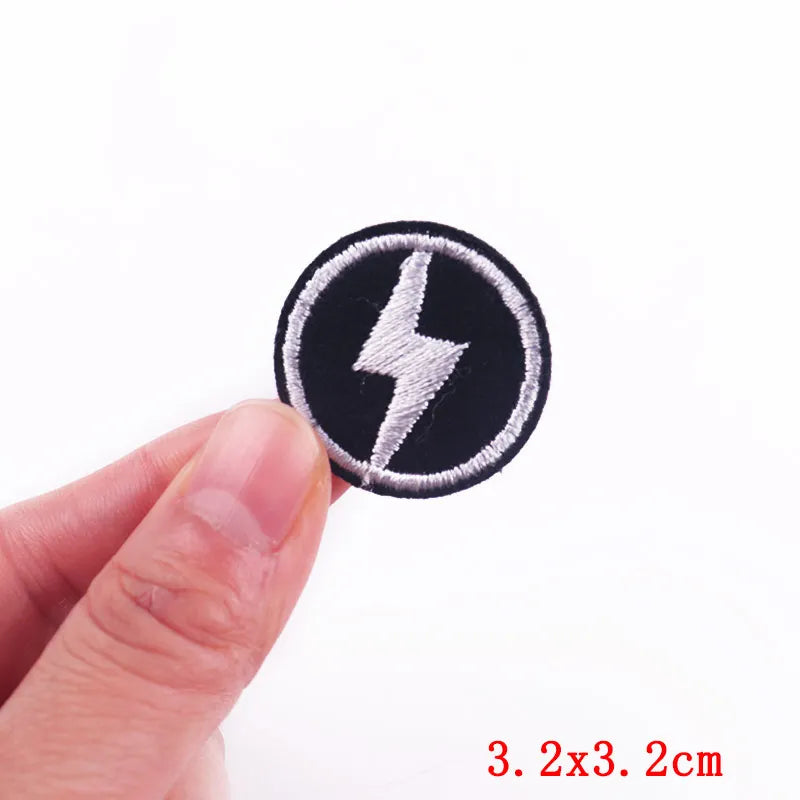 Black and white lightning bolt patch held between fingers with size label '3.2x3.2cm' on a white background