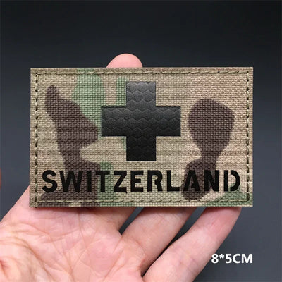 Switzerland flag Camouflage patch held in a hand against a dark background