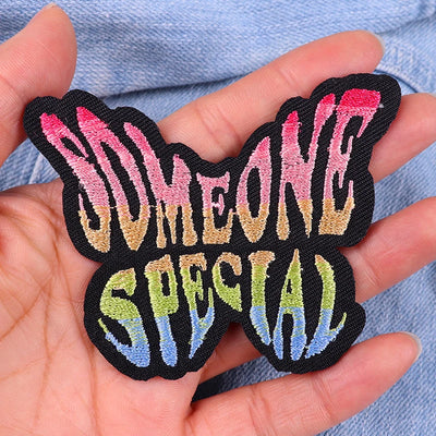Embroidered patch with 'Someone Special' text held in a hand against a denim background