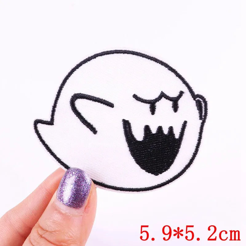 Ghost face patch held by a hand with purple nail polish on a white background