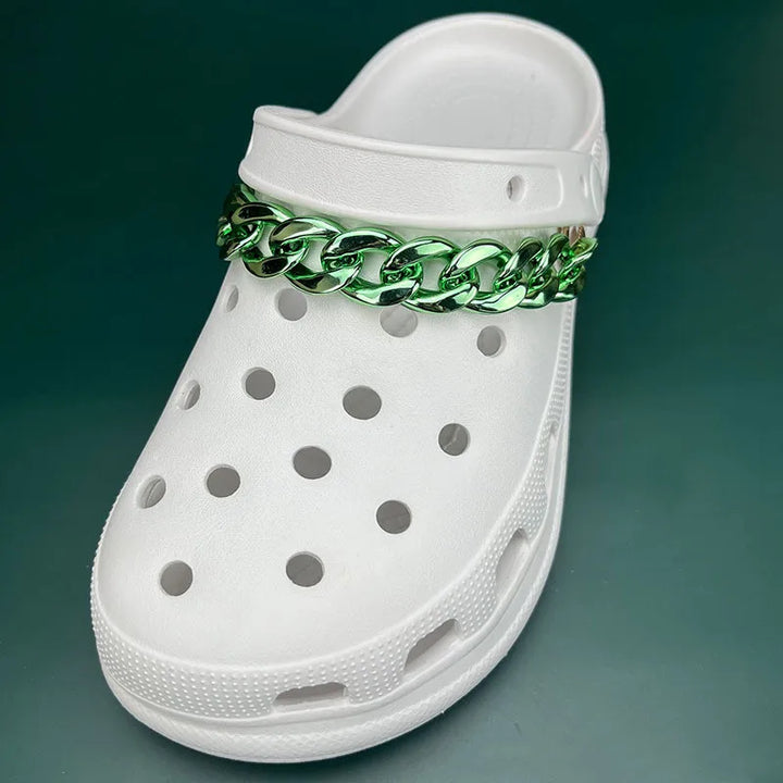 White clog shoe with a green chain accessory on a dark green background