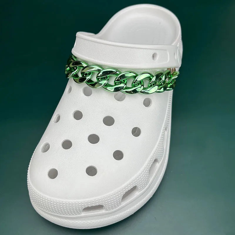 White clog shoe with a green chain accessory on a dark green background