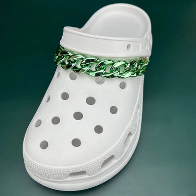 White clog shoe with a green chain accessory on a dark green background