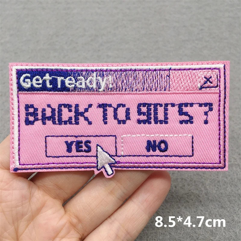 Pink patch with text and design held by a hand on a gray background