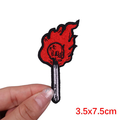 Red and black flame-shaped patch held by a hand with measurement text '3.5x7.5cm'.