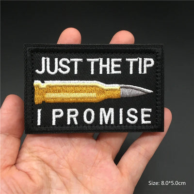 Embroidered patch with a bullet graphic and text held in a hand against a dark background