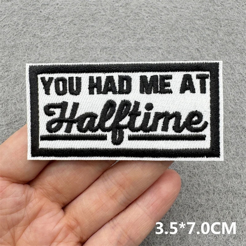 Embroidered patch with 'You Had Me at Halftime' text held in a hand against a gray background.