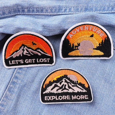 Three adventure-themed patches on a denim background