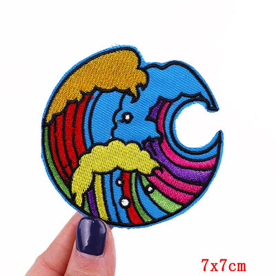 Colorful embroidered patch of a cartoon character with a rainbow design held by a hand.