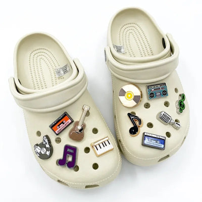 Beige clogs with various music-themed charms on a white background