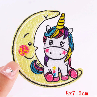 Embroidered patch of a unicorn and moon with colorful hair held by a hand.