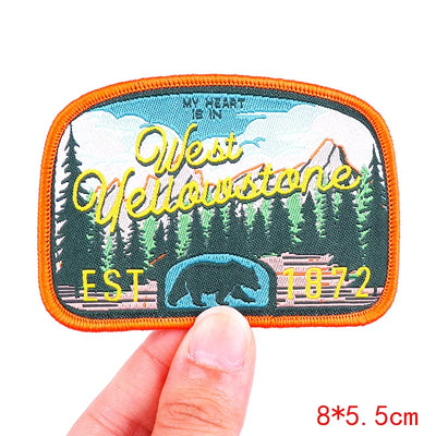 Embroidered patch with 'West Yellowstone' design held by a hand on a white background