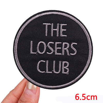Round patch with 'The Losers Club' text held by a hand, size indicated as 6.5cm.