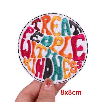 Round patch with colorful text 'Treat people with kindness' held by a hand, size 8x8cm.