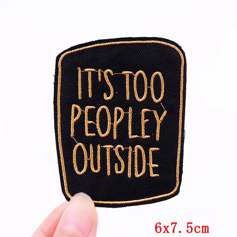 Embroidered patch with 'It's Too Peopley Outside' text held by a hand on a white background