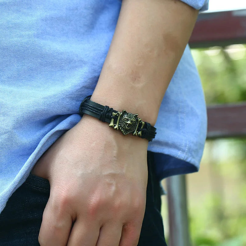 Person wearing a black leather bracelet with a metal clasp on a blurred outdoor background
