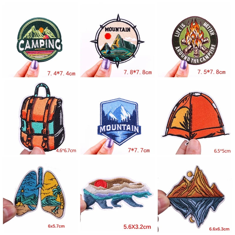 Collection of camping-themed patches with measurements held by fingers on a white background.