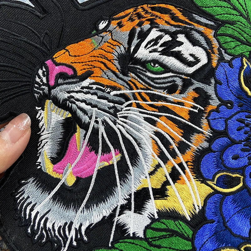 Embroidered patch of a tiger face with colorful details on a black background