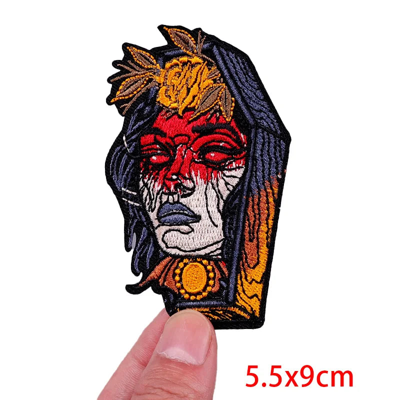 Decorative patch with a stylized face design held by a finger, on a white background.