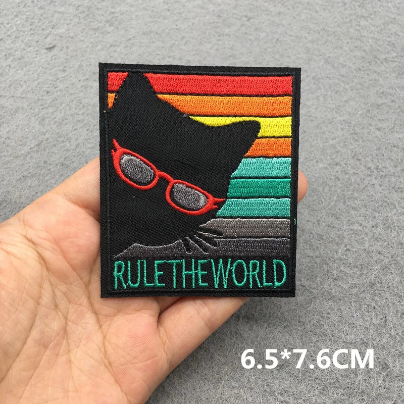 Patch with a black cat wearing sunglasses and 'RULE THE WORLD' text on a gray background