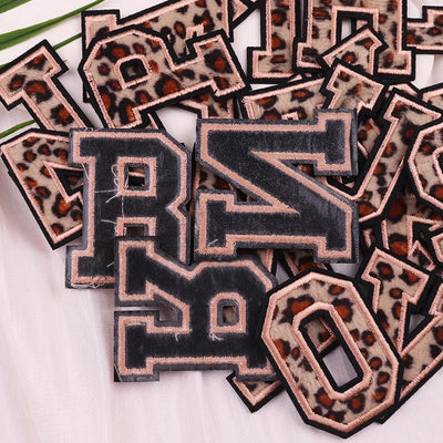 Leopard print letter patches on a white background