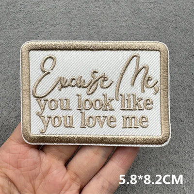 Embroidered patch with text held by a hand on a gray background