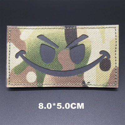 Camouflage patch with a smiley face design on a dark background