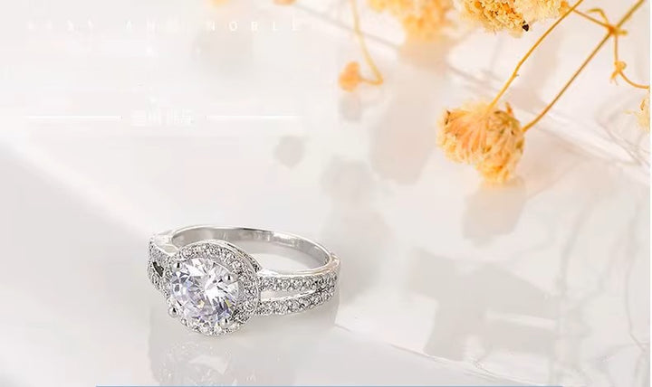 Silver ring with a large crystal on a white surface with dried flowers.