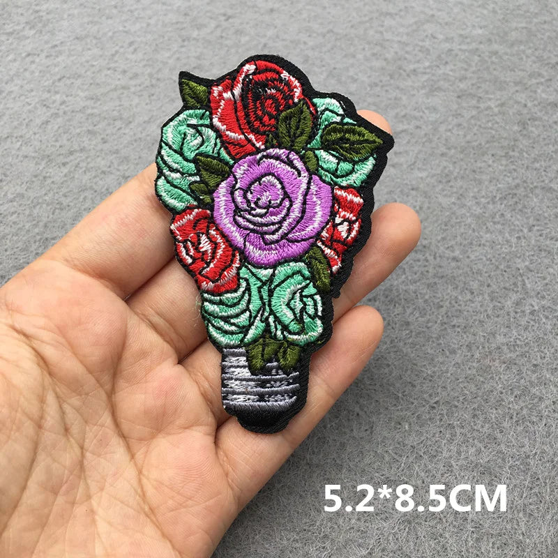 Floral patch held in a hand with dimensions displayed on a gray background