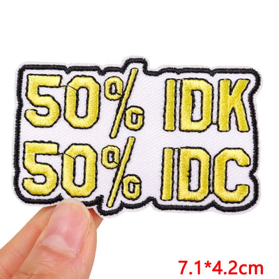 Embroidered patch with '50% IDK, 50% IDC' text held by a hand on a white background.