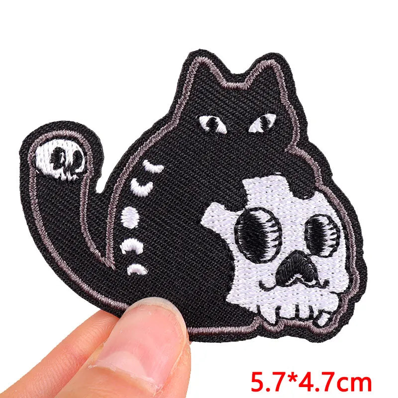 Black cat skull patch held by a hand with size indication on a white background
