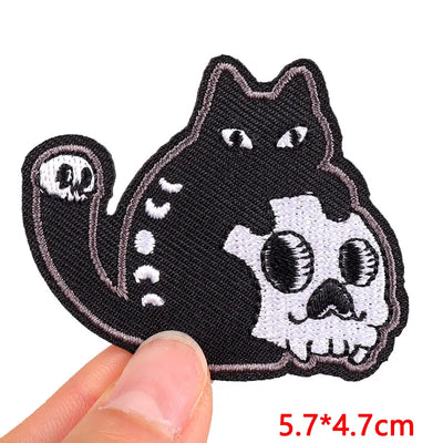 Black cat skull patch held by a hand with size indication on a white background