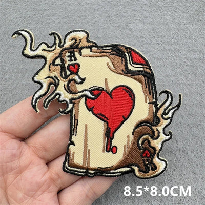 Embroidered patch with a design of a goat holding a heart, held in a hand against a gray background.