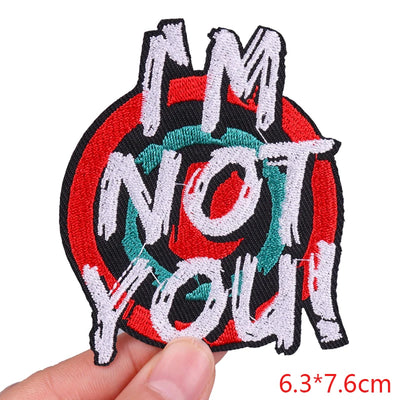 Embroidered patch with text 'I AM NOT YOU' held by a hand on a white background