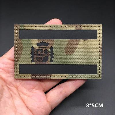 Spain flag Camouflage patch held in a hand against a dark background