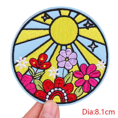 Colorful patch with flowers and sun held by a hand, labeled 'Dia:8.1cm'.