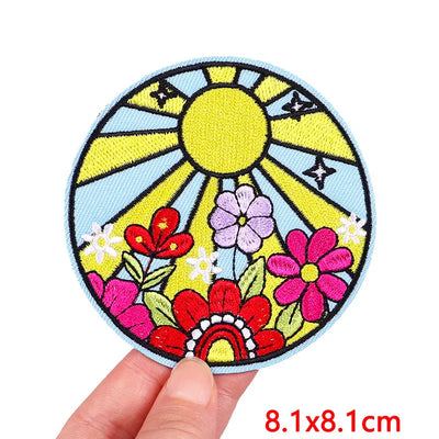 Colorful patch with sun and flowers held by a hand, size 8.1x8.1cm.