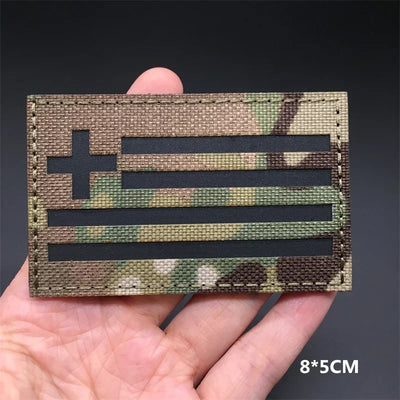 Greece Camouflage flag patch held in a hand with a dark background