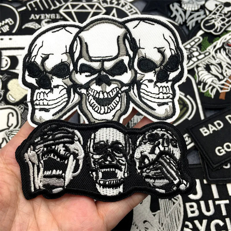 Skull-themed patches held in a hand with various other patches in the background.