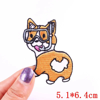 Embroidered patch of a dog with goggles held by a hand on a white background