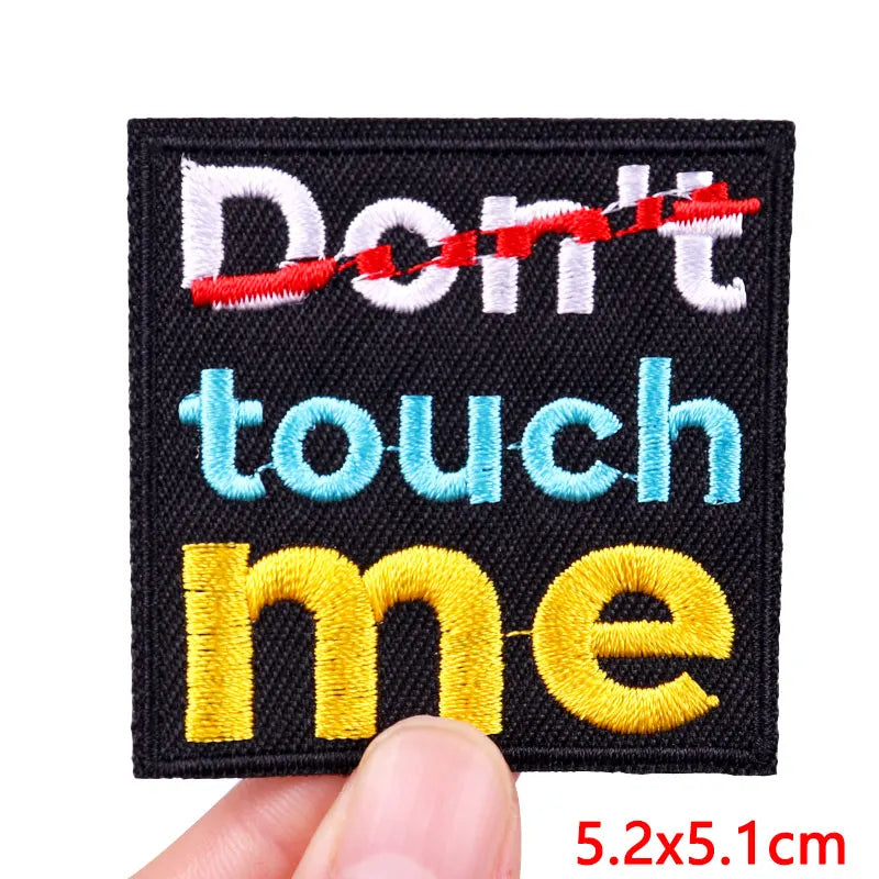 Embroidered patch with 'Don't touch me' text held by a hand, on a white background.