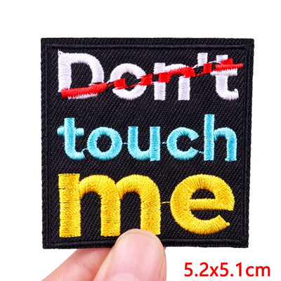 Embroidered patch with 'Don't touch me' text held by a hand, on a white background.