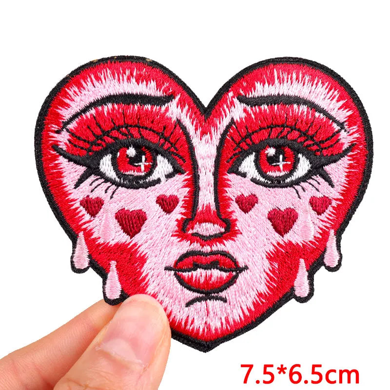 Heart-shaped patch with face design held by a hand, on a white background