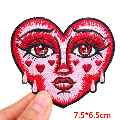 Heart-shaped patch with face design held by a hand, on a white background